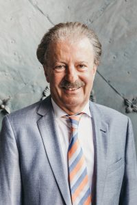 Der Leiter der Adler Apotheke Prof. Mag. Bernd Milenkovics in einem hellblauen Anzug.