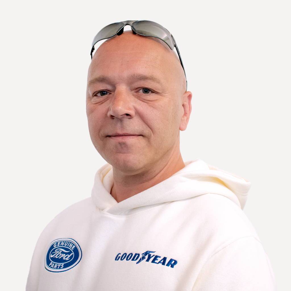 Mitarbeiter der Adler Apotheke, lächelt in einem weißen Hoodie.
